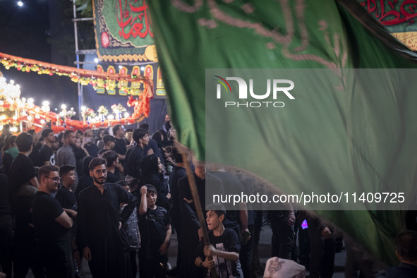 A young Iraqi boy is holding a religious flag while participating in a religious rally to commemorate Tasoua in the Dolatabad neighborhood i...