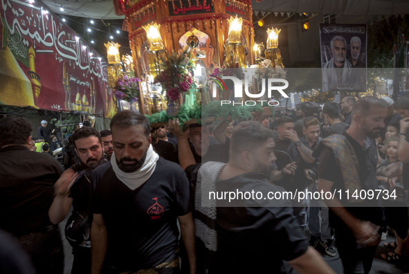 An Iraqi worshipper living in Iran is carrying a religious symbol while participating in a religious rally to commemorate Tasoua, in Dolatab...