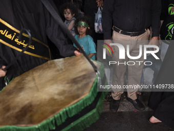 A young girl is wearing a religious headband and is participating in a religious rally to commemorate Tasoua in Dolatabad neighborhood in so...