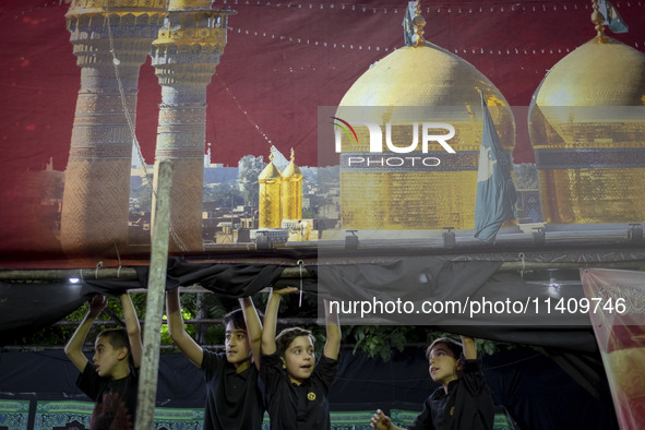 Young boys are standing under a religious banner while they are participating in a religious rally to commemorate Tasoua, in Dolatabad neigh...