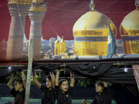 Young boys are standing under a religious banner while they are participating in a religious rally to commemorate Tasoua, in Dolatabad neigh...