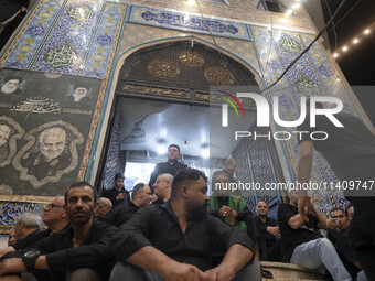 Iraqi men living in Iran are sitting just outside a mosque while they are participating in a religious rally to commemorate Tasoua, in Dolat...