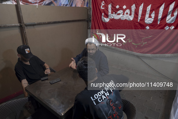 A cleric is speaking with two young men during a religious rally to commemorate Tasoua, in Dolatabad neighborhood in southern Tehran, Iran,...