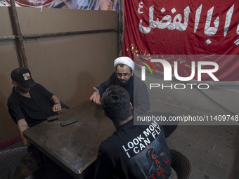 A cleric is speaking with two young men during a religious rally to commemorate Tasoua, in Dolatabad neighborhood in southern Tehran, Iran,...