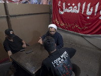 A cleric is speaking with two young men during a religious rally to commemorate Tasoua, in Dolatabad neighborhood in southern Tehran, Iran,...