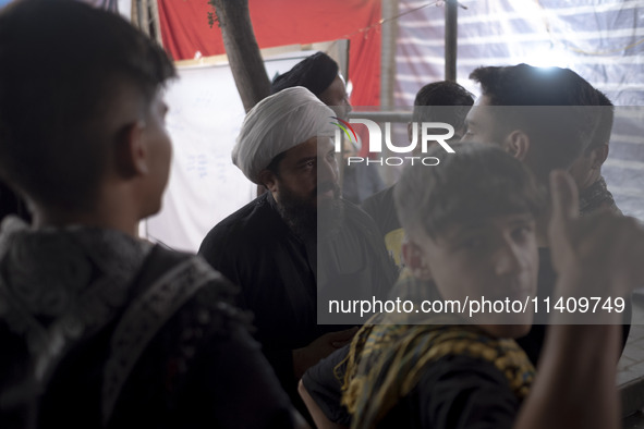 A cleric is speaking with young Iranian men during a religious rally to commemorate Tasoua, in Dolatabad neighborhood in southern Tehran, Ir...