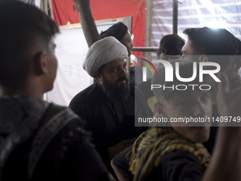 A cleric is speaking with young Iranian men during a religious rally to commemorate Tasoua, in Dolatabad neighborhood in southern Tehran, Ir...