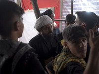 A cleric is speaking with young Iranian men during a religious rally to commemorate Tasoua, in Dolatabad neighborhood in southern Tehran, Ir...