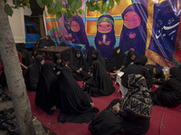 Veiled Iranian women are sitting together in front of a banner featuring cartoon faces of veiled young girls, during a religious rally to co...