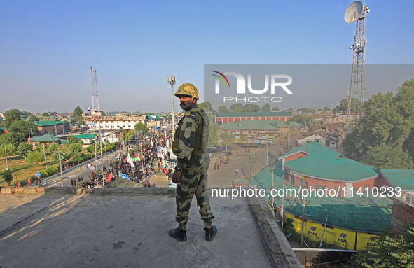 An Indian paramilitary soldier is keeping vigil from the top of a building as thousands of Shia Muslims are attending the mourning processio...