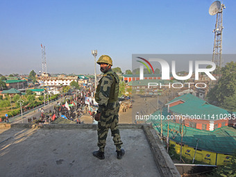 An Indian paramilitary soldier is keeping vigil from the top of a building as thousands of Shia Muslims are attending the mourning processio...