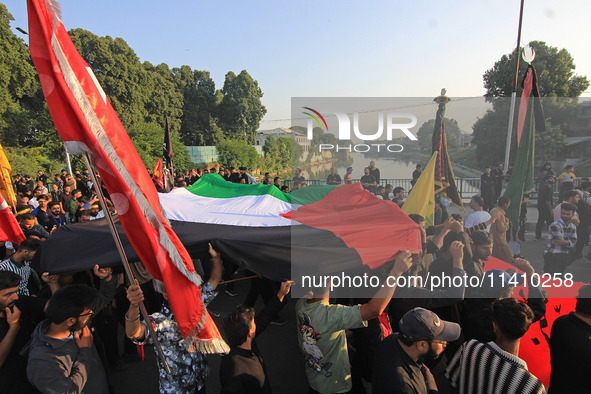 Shia mourners are carrying the Palestine flag as thousands are attending the mourning procession to commemorate the martyrdom of Prophet Muh...