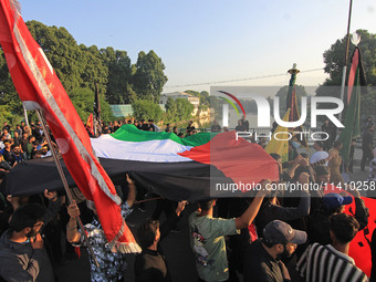 Shia mourners are carrying the Palestine flag as thousands are attending the mourning procession to commemorate the martyrdom of Prophet Muh...