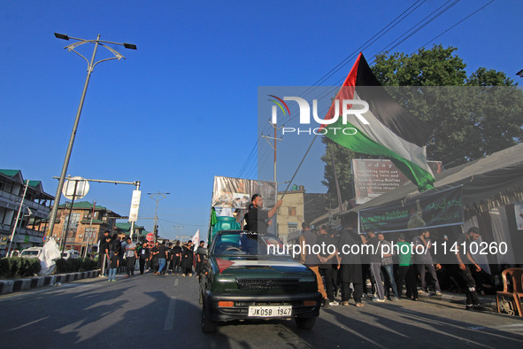 A Shia mourner is carrying a Palestine flag as thousands of Shia Muslims are attending the mourning procession to commemorate the martyrdom...