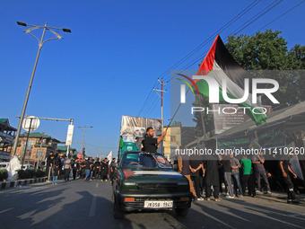 A Shia mourner is carrying a Palestine flag as thousands of Shia Muslims are attending the mourning procession to commemorate the martyrdom...