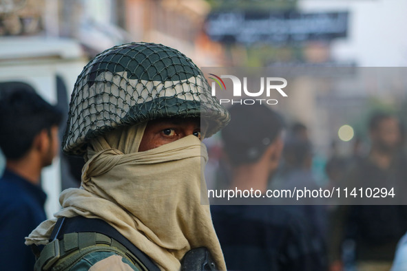 An Indian security personnel is standing guard as Kashmiri Shiite Muslim mourners are taking part in a Muharram procession on the eighth day...