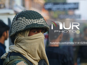 An Indian security personnel is standing guard as Kashmiri Shiite Muslim mourners are taking part in a Muharram procession on the eighth day...