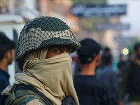 An Indian security personnel is standing guard as Kashmiri Shiite Muslim mourners are taking part in a Muharram procession on the eighth day...