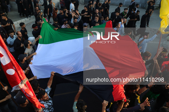 Kashmiri Shiite Muslim mourners are carrying a Palestinian flag and shouting anti-Israel and anti-US slogans as they take part in a Muharram...