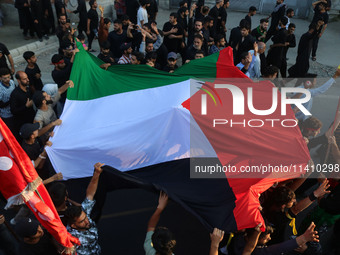 Kashmiri Shiite Muslim mourners are carrying a Palestinian flag and shouting anti-Israel and anti-US slogans as they take part in a Muharram...