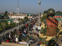 An Indian security personnel is standing guard as Kashmiri Shiite Muslim mourners are taking part in a Muharram procession on the eighth day...