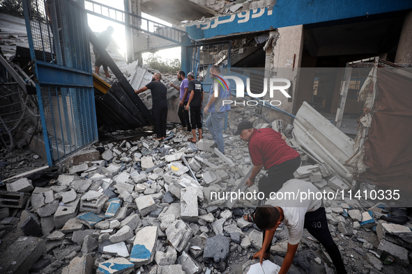 People are checking the destruction at a school run by the UN Relief and Works Agency for Palestine Refugees (UNRWA) that was previously hit...