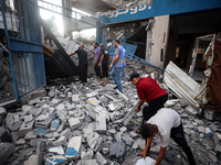 People are checking the destruction at a school run by the UN Relief and Works Agency for Palestine Refugees (UNRWA) that was previously hit...