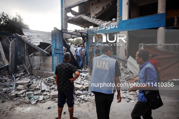 People are checking the destruction at a school run by the UN Relief and Works Agency for Palestine Refugees (UNRWA) that was previously hit...