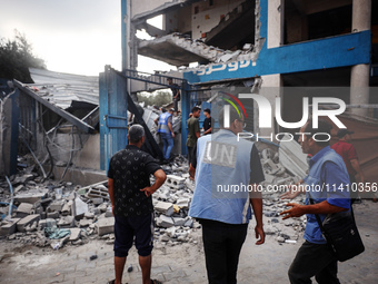 People are checking the destruction at a school run by the UN Relief and Works Agency for Palestine Refugees (UNRWA) that was previously hit...