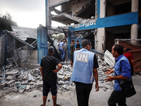 People are checking the destruction at a school run by the UN Relief and Works Agency for Palestine Refugees (UNRWA) that was previously hit...