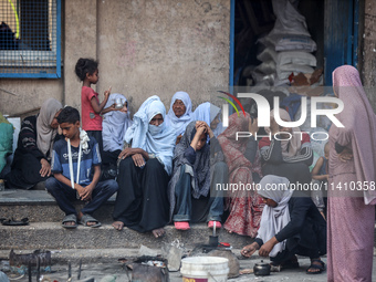 Palestinians are sitting inside a school run by the UN Relief and Works Agency for Palestine Refugees (UNRWA) that was previously hit by Isr...