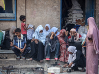 Palestinians are sitting inside a school run by the UN Relief and Works Agency for Palestine Refugees (UNRWA) that was previously hit by Isr...