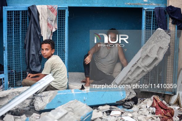 Palestinians are sitting inside a school run by the UN Relief and Works Agency for Palestine Refugees (UNRWA) that was previously hit by Isr...