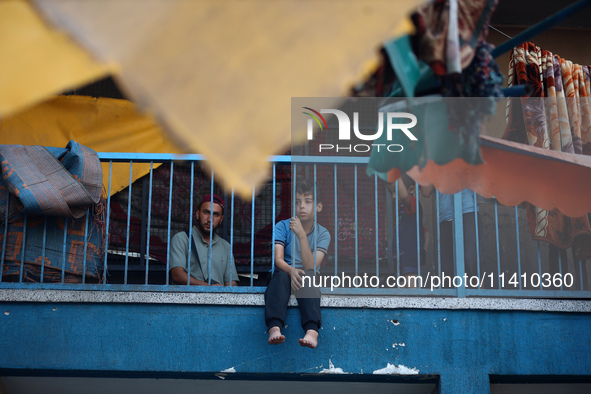 A Palestinian boy is watching as people are checking the destruction at a school run by the UN Relief and Works Agency for Palestine Refugee...