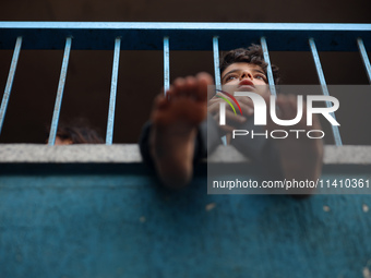 A Palestinian boy is watching as people are checking the destruction at a school run by the UN Relief and Works Agency for Palestine Refugee...