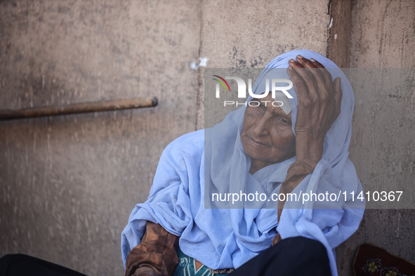 An injured woman is sitting at a school run by the UN Relief and Works Agency for Palestine Refugees (UNRWA) that was previously hit by Isra...