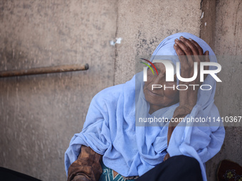 An injured woman is sitting at a school run by the UN Relief and Works Agency for Palestine Refugees (UNRWA) that was previously hit by Isra...