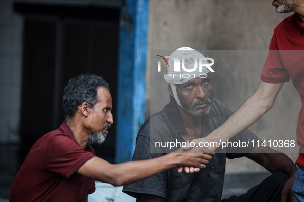 An injured man is sitting at a school run by the UN Relief and Works Agency for Palestine Refugees (UNRWA) that was previously hit by Israel...