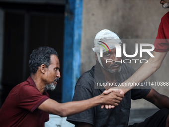 An injured man is sitting at a school run by the UN Relief and Works Agency for Palestine Refugees (UNRWA) that was previously hit by Israel...