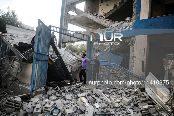 People are checking the destruction at a school run by the UN Relief and Works Agency for Palestine Refugees (UNRWA) that was previously hit...