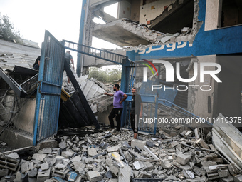 People are checking the destruction at a school run by the UN Relief and Works Agency for Palestine Refugees (UNRWA) that was previously hit...