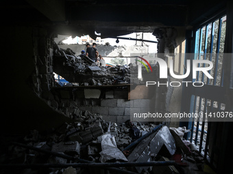 People are checking the destruction at a school run by the UN Relief and Works Agency for Palestine Refugees (UNRWA) that was previously hit...