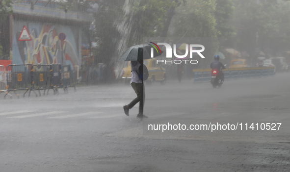 A man is crossing a road during heavy monsoon rain in Kolkata, India, on July 15, 2024. 