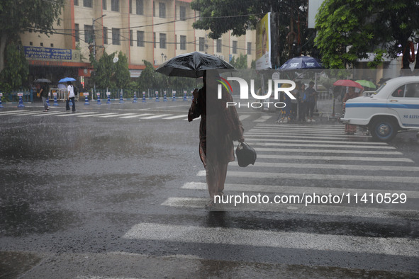 A woman is crossing a road during heavy monsoon rain in Kolkata, India, on July 15, 2024. 