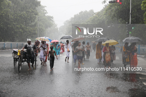 Commuters are walking on a road with umbrellas during heavy monsoon rain in Kolkata, India, on July 15, 2024. 