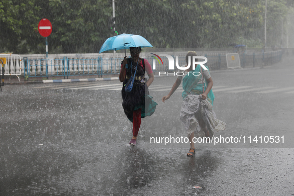 Women are crossing a road during heavy monsoon rain in Kolkata, India, on July 15, 2024. 