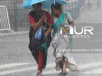 Women are crossing a road during heavy monsoon rain in Kolkata, India, on July 15, 2024. (