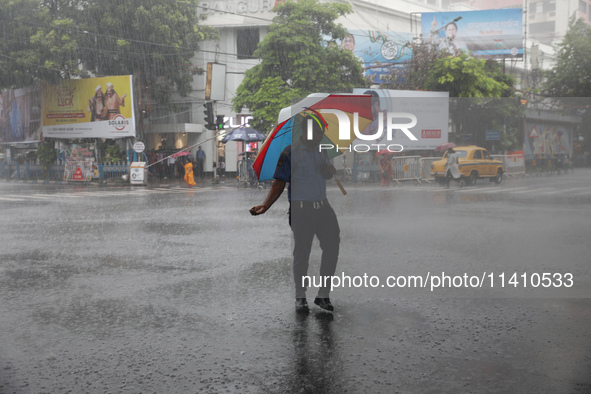 A civic volunteer is standing on a road crossing during heavy monsoon rain in Kolkata, India, on July 15, 2024. 