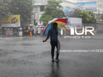 A civic volunteer is standing on a road crossing during heavy monsoon rain in Kolkata, India, on July 15, 2024. (