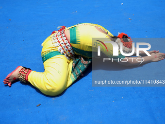 An artist is offering prayer after performing on the last day of the week-long celebration of Rath Yatra, or chariot procession, in Kolkata,...